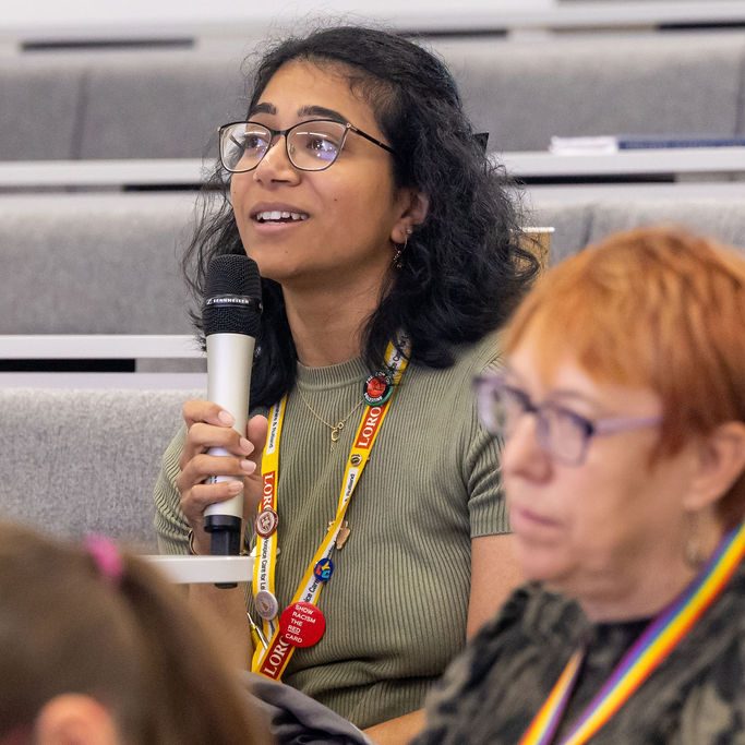 Multiple audience members watching a presenter towards the left.