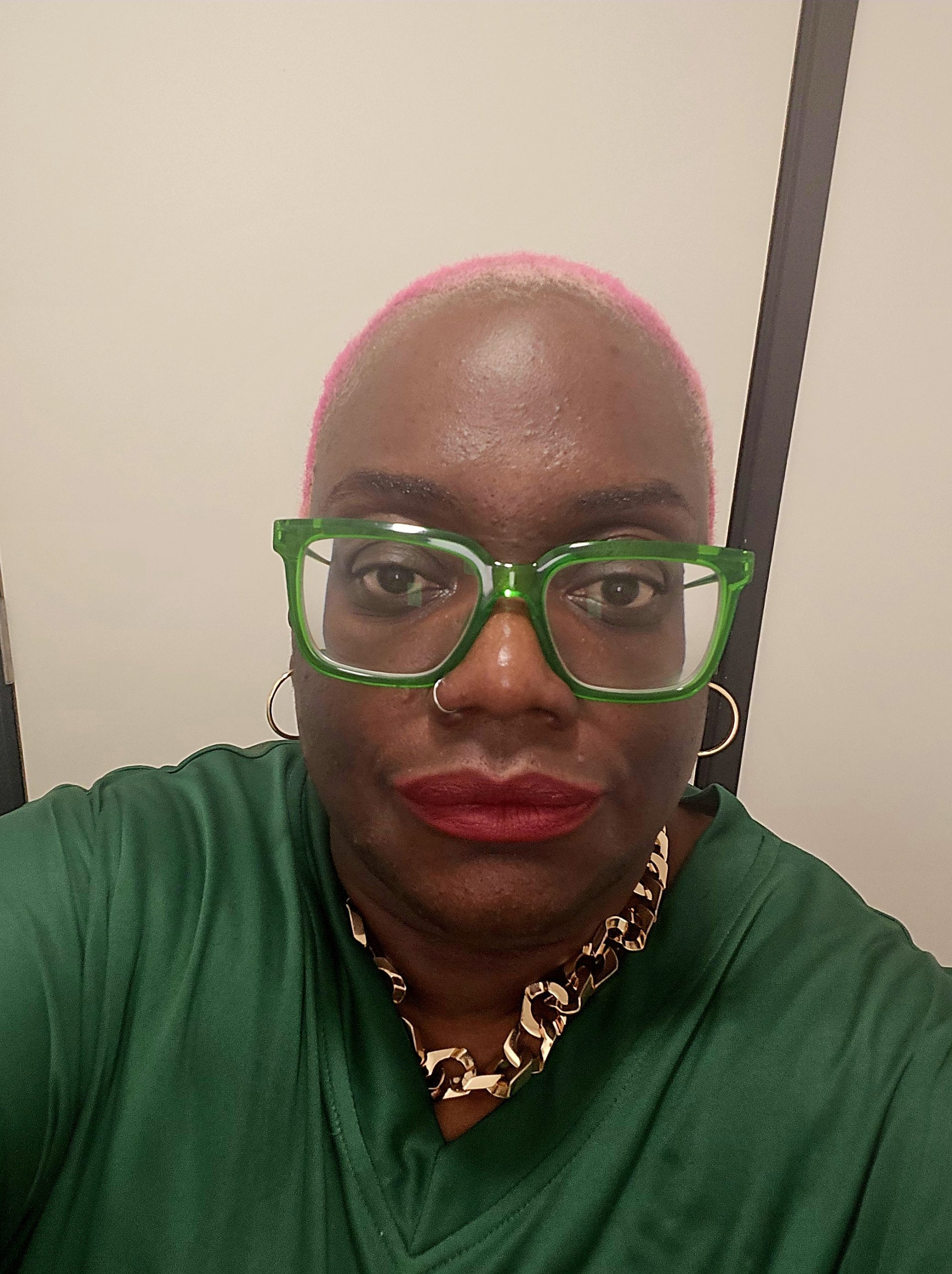 Nysha wearing green glasses, looking straight ahead.
